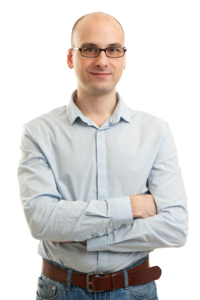 Smiling man standing with his arms folded against white background